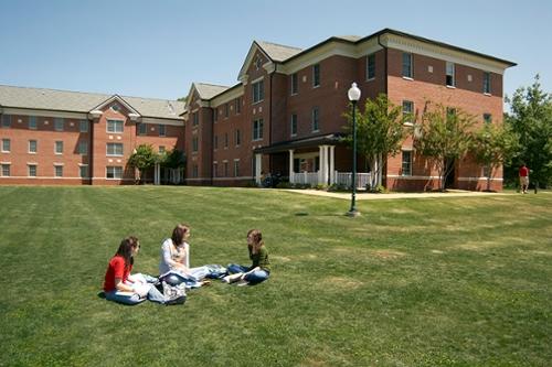 坎德勒大厅的外部夏季视图，前景中有三个学生在学习